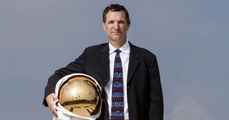 Thomas Müller holding a space helmet, preparing for a space mission or demonstration