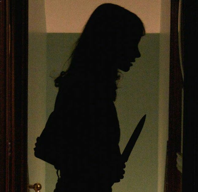 A girl holding a knife, looking distressed and conflicted.