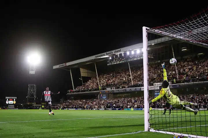 Clarke Oduor of Grimsby Town shooting a penalty against Manchester United, showing concentration and striking technique.