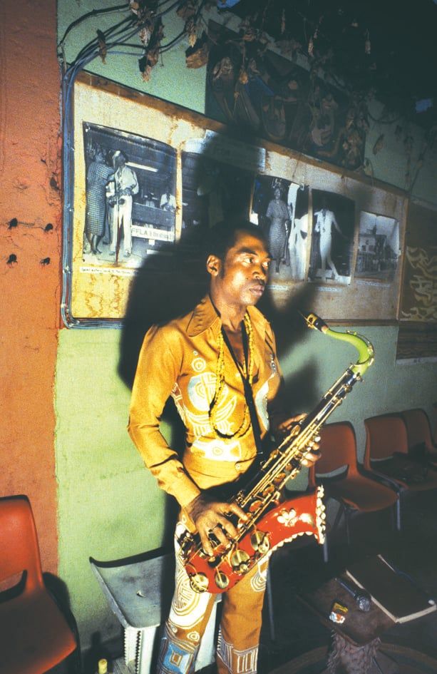 Fela Kuti holding his trumpet in a relaxed pose offstage.